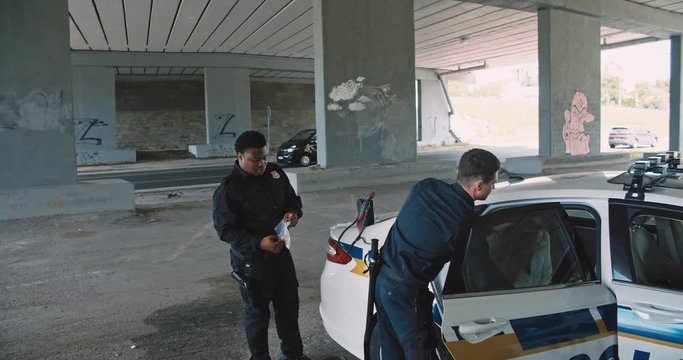 Policemen arresting pretty girl young offender and putting into a patrol car. Two cops catch a female drug dealer in the street.