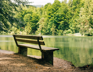 Fototapeta na wymiar Bench and reflected trees near a lake