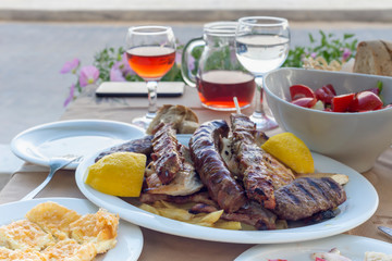 The traditional Greek snacks grilled (soufflaki), chicken pieces, cutlet and a glass of wine close-up