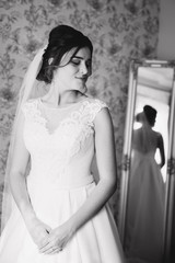 Naklejka premium Beautiful bride stand by the window. Morning with sunlights. Black and white photo
