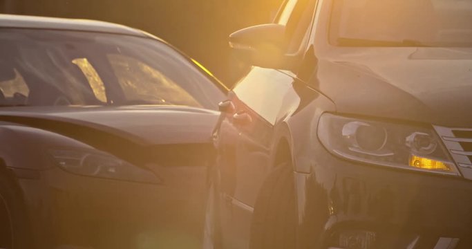 Car accident in the city. View of two modern cars crashed standing stuck on the road at sunset. Traffic collision.