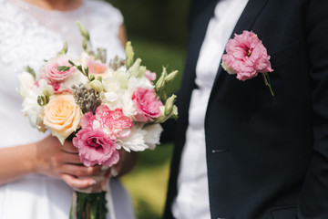 Wedding bouquet in brides hands. Close up view of couples hands holding wedding bouquet. Flowers