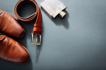Businessman's accessories. Brown leather shoes, belt, perfume, golden rings. Male fashion. Businessman