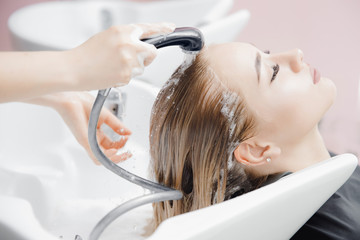 Fototapeta premium Washing hair of beautiful blonde girl in beauty salon, coloring