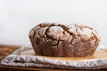 Yeast free homemade bread with whole rye and wheat grains on rustic wooden background.