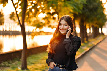 Fashion happy cool smiling girl talking on smartphone in colorful clothes oin th park