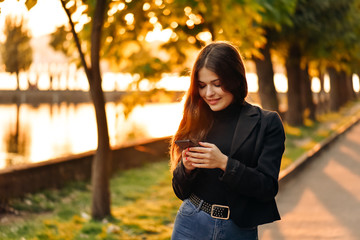 Happy girl using a smart phone in a city park. 