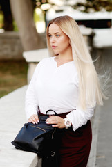 Young stylish woman wearing neutral blazer and hat walking on the city street in spring. Casual fashion, elegant look. Plus size model.