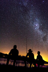 Grupo de amigos pescando a la luz de la Vía láctea