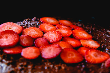 Sliced strawberry cut on a cake on a tray before baking it, with a heart shape.