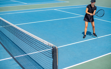 Young sports woman playing tennis on the blue tennis court