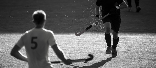 Hockey player with ball in attack playing field hockey game