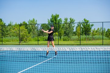 Young sports woman playing tennis on the blue tennis court