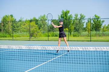 Fototapeta na wymiar Young sports woman playing tennis on the blue tennis court