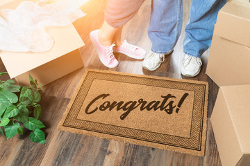 Man and Woman Unpacking Near Welcome Mat with Congrats, Moving Boxes and Plant
