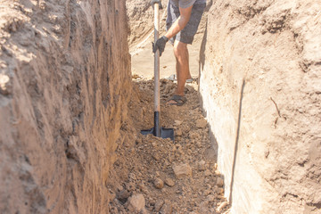 A worker digs a hole using a shovel / house building