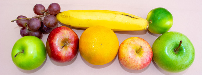 Colorful fruits in a row next to two bananas on the table
