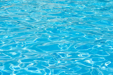 Waves and clear blue water surface  in the swimming pool of a resort .