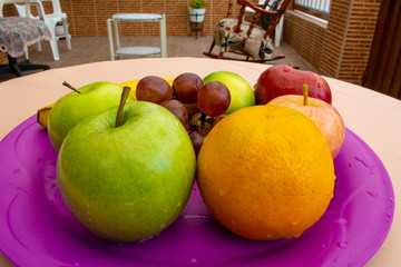 Apples, bananas, grapes, a lemon and an orange on the tray close up