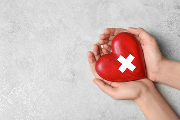 Woman holding heart on grey stone background, top view with space for text. Donation concept