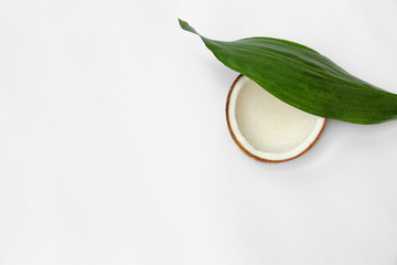 Half of fresh coconut and palm leaf on white background, top view