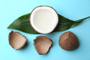 Obraz na płótnie Canvas Fresh coconuts and palm leaf on light blue background, flat lay