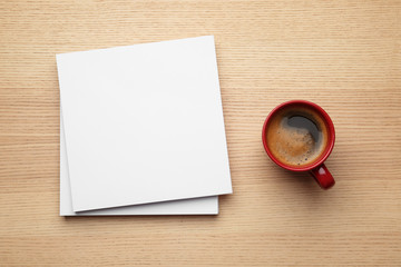 Obraz na płótnie Canvas Blank paper sheets for brochure and cup of coffee on wooden background, flat lay. Mock up