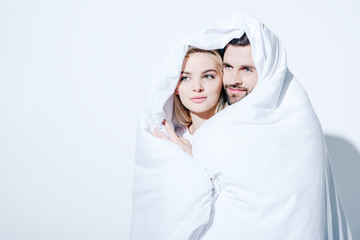 beautiful girlfriend and handsome boyfriend covered in blanket on white