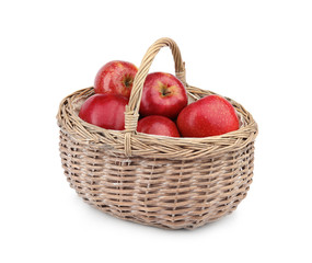 Wicker basket of ripe juicy red apples on white background