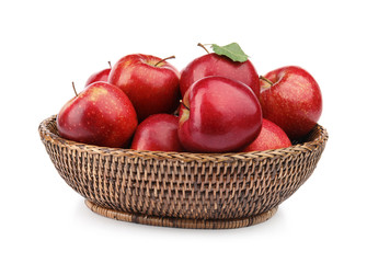 Wicker bowl of ripe juicy red apples with leaf on white background