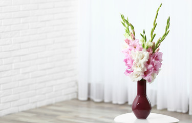 Vase with beautiful gladiolus flowers on wooden table indoors. Space for text - obrazy, fototapety, plakaty