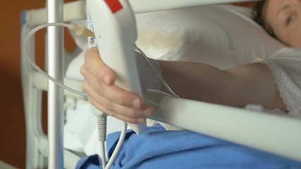 Patient after anesthesia trying to press the red emergency button to call a nurse for help in hospital. Exhausted woman after surgery can't push an emergency button, very emotional moment in close-up