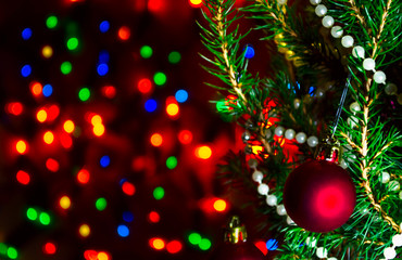 Red Christmas ball on Christmas tree with blurred lights. Christmas ball and lights on dark blur background. Christmas card with blurred lights. Background with bokeh of Christmas lights. Copy space.