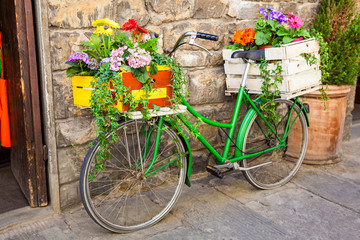 Fototapeta na wymiar Green bicycle decorated with flowers parked in Florence