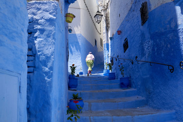 A local woman walks the streets of an old medina in a blue city Chefchaouen in Morocco.
