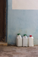 Old white bottles of insecticide next to a wall