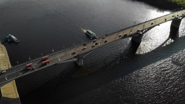 Nice aerial footage of a bridge with cars and busses with ship going down the river under bridge.
