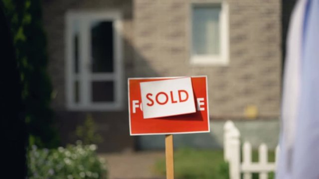 Letting agent giving keys from apartment to new owner against sold signboard