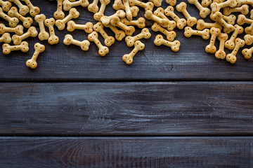 Dry dog food in shape of bone on wooden background top view copyspace