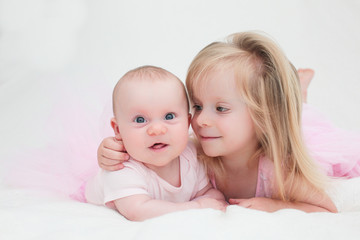 Two Sisters, One Cute 3 Years Old Toddler Girl and 4 Month Old Cute Baby Girl, Infant, Playing on the white bed, New family concept, The most Beautiful Girls Princesses 