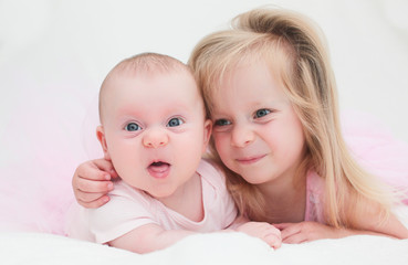 Two Sisters, One Cute 3 Years Old Toddler Girl and 4 Month Old Cute Baby Girl, Infant, Playing on the white bed, New family concept, The most Beautiful Girls Princesses 
