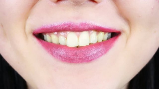 Extreme close-up of lips of a young woman. Woman paints her lips with bright lipstick for makeup. Women's morning makeup