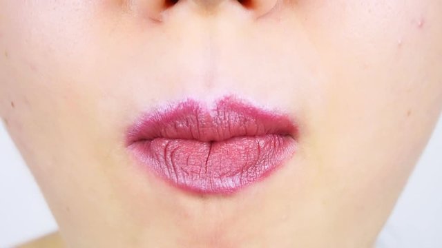 Extreme close-up of lips of a young woman. Woman eating a slice of dark chocolate with filling. Women's morning makeup