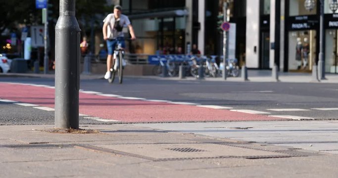Street view of people walk cross the road, cyclist and rider ride bicycle and E-scooter on bicycle lane at pedestrian crossing and blur background of cityscape on K&ouml;nigsallee in D&uuml;sseldorf, Germany.