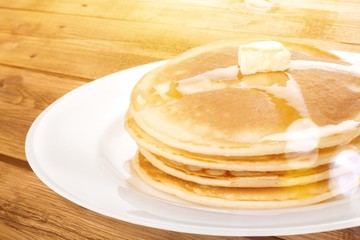 Stack of tasty pancakes with butter on a white plate