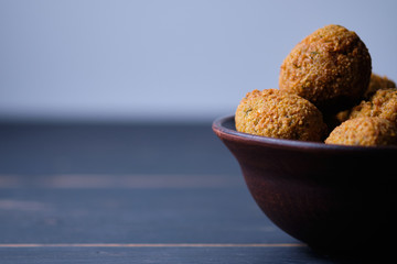 Classic hummus balls in a clay plate on a wooden table. National, vegetarian dish. General form.