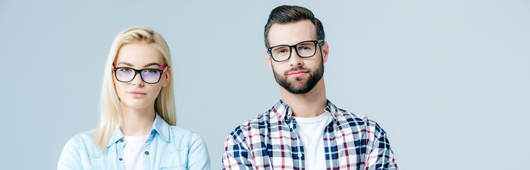 panoramic shot of man and beautiful girl in glasses looking at camera isolated on grey