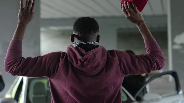 Shot back african american offender in mask stand hands up in patrol car in handcuffs burglar crime hold danger gangster gun robber handgun illegal law outlaw arrest bad guy close up slow motion