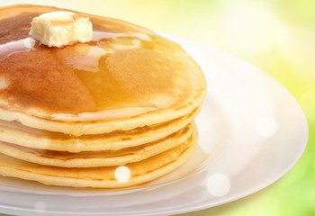 Stack of tasty pancakes with butter on a white plate