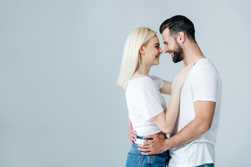 beautiful young couple embracing and smiling isolated on grey with copy space